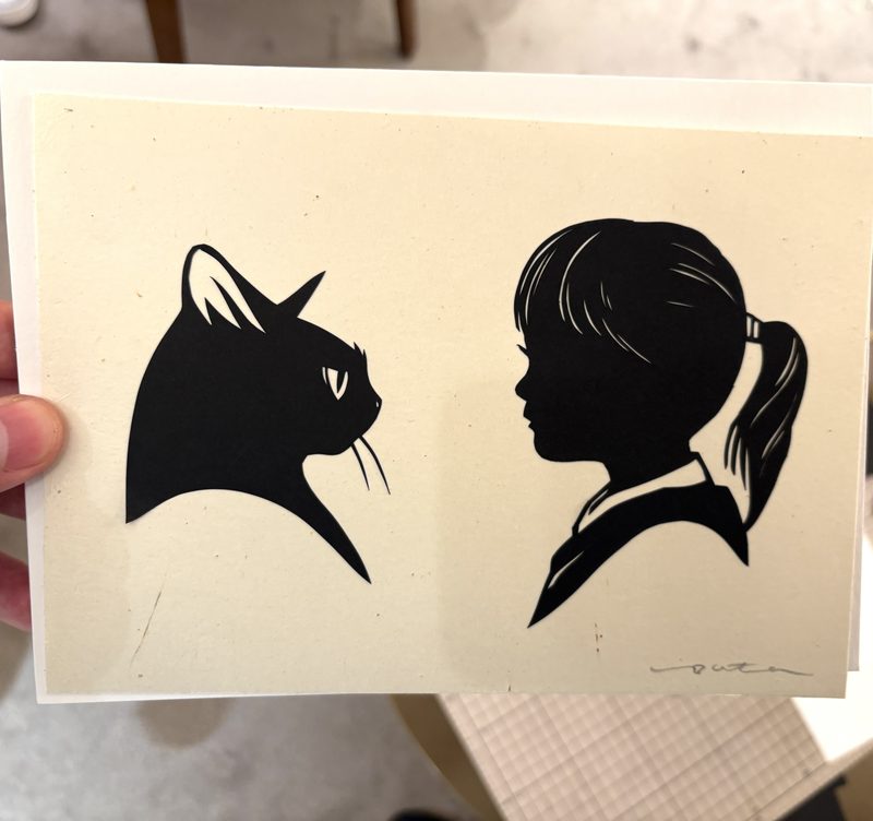 猫の横顔と人物の横顔のシルエット切り絵